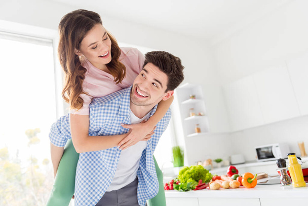Portrait of tender gentle passionate two people couple vegan man hug piggyback woman enjoy weekend dish meal dinner preparation have rest relax leisure in kitchen house indoors - Photo, Image