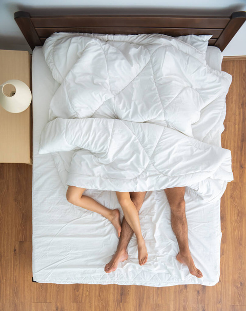 Battaniyenin altındaki çift yatakta yatıyordu. Yukarıdan görünüm - Fotoğraf, Görsel