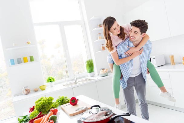 Two people funky spouses passionate man carry piggyback girl enjoy hobby weekend dinner supper lunch preparation hug in kitchen house indoors - Valokuva, kuva