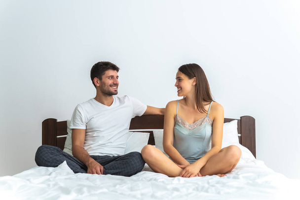 The man and a woman sitting on the bed on the white background - Foto, imagen