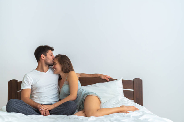 幸せな男と女は白い背景にベッドの上でキス - 写真・画像