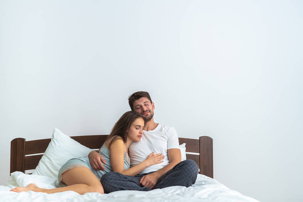 L'uomo felice e una donna seduti sul letto sullo sfondo bianco - Foto, immagini