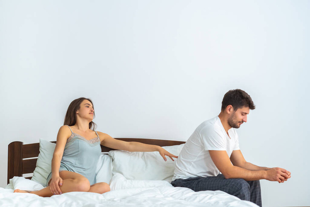 O homem e uma mulher sentados na cama no fundo branco - Foto, Imagem