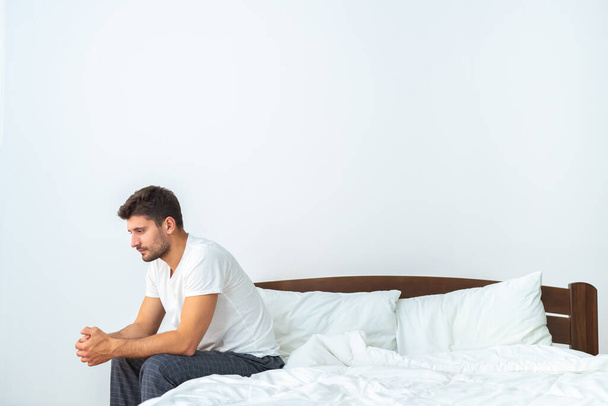 The depressed man sitting on the bed on the white background - Photo, Image