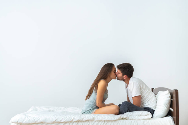 Šťastný pár na posteli líbání na bílém pozadí - Fotografie, Obrázek