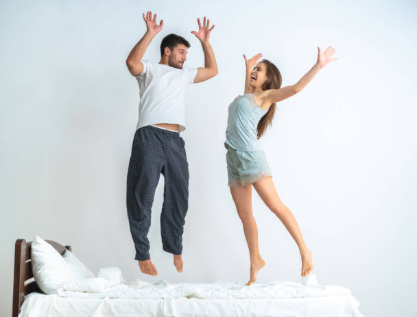 La coppia che salta sul letto sullo sfondo bianco - Foto, immagini