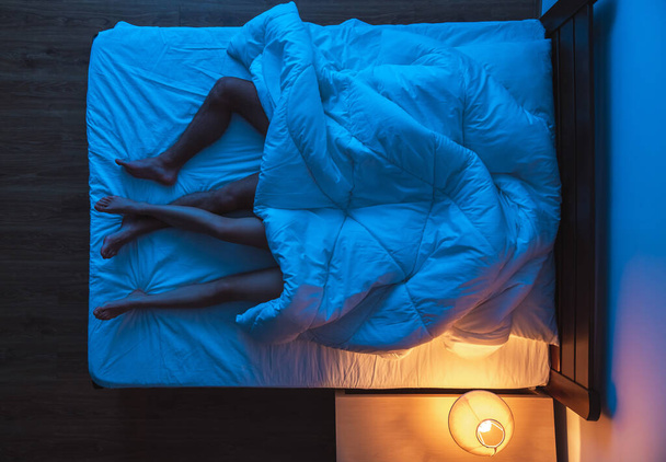 Το ζευγάρι ξαπλωμένο κάτω από ένα πάπλωμα στο κρεβάτι. βραδινή νύχτα, θέα από ψηλά - Φωτογραφία, εικόνα