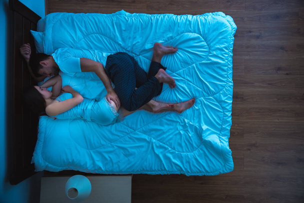 Чоловік і жінка сплять на ліжку. вечірній нічний час, вид зверху
 - Фото, зображення