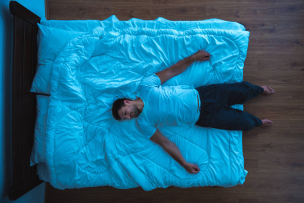 Muž ležící na posteli. pohled shora, večerní noční čas - Fotografie, Obrázek
