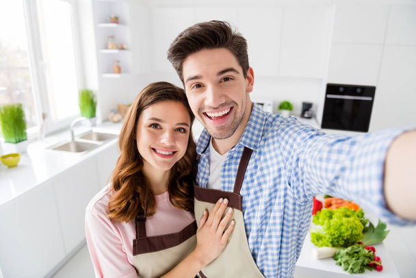 Self-portrait of his he her she two nice attractive positive cheerful spouses cooking domestic homemade dish spending weekend in light white interior kitchen house apartment indoors - Fotó, kép