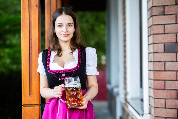 Hermosa chica Oktoberfest usando un vestido bávaro tradicional sosteniendo tazas de cerveza. Sexy mujer rusa en vestido con cerveza. - Foto, Imagen