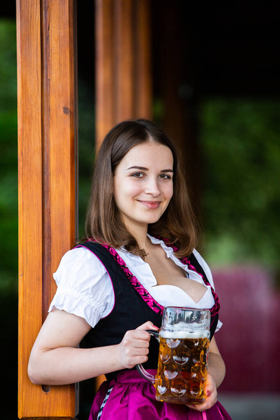 Красивая девушка с фестиваля Октоберфест в традиционном баварском платье с пивными кружками. Сексуальная русская женщина в платье с пивом. - Фото, изображение