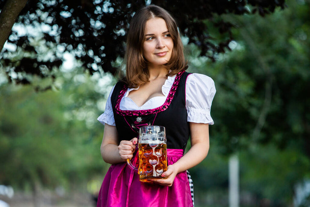 Bella ragazza Oktoberfest indossa un abito tradizionale bavarese che tiene tazze di birra. Sexy donna russa in abito con birra. - Foto, immagini