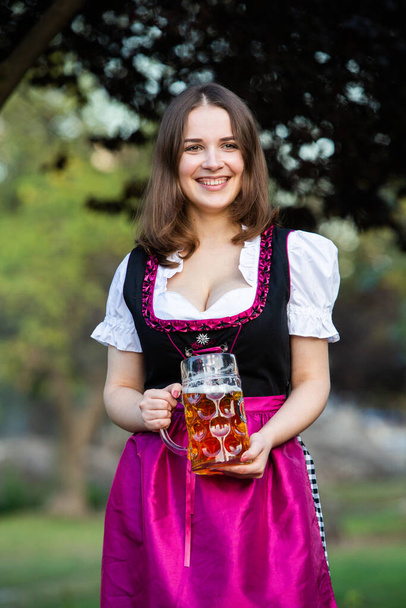 Piękna dziewczyna z Oktoberfest w tradycyjnej bawarskiej sukience z kubkami piwa. Sexy Rosjanka w sukience z piwem. - Zdjęcie, obraz