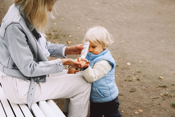 Mother applies sanitizer on her little sons hands. - Fotografie, Obrázek