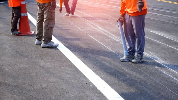 Matala osa Road Workers ryhmä työskentelee merkintä linja maalaus liikenteen väri linjat asfalttitiellä kanssa rautatien raiteen rajan kadun pinnalla kaupungissa, valikoiva painopiste - Valokuva, kuva