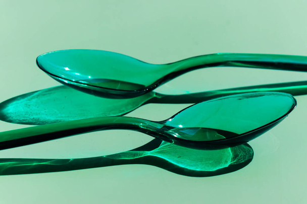 Zwei grüne, transparente Plastiklöffel mit kontrastierenden Schatten - Foto, Bild