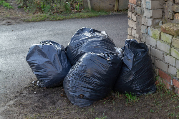Garbage bags full of leaves on the sidewalk in front of a fence - a Royalty  Free Stock Photo from Photocase