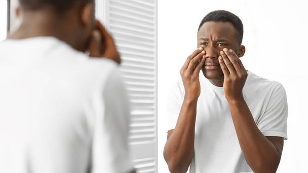 Concerned African Man Touching Bags Under Eyes Standing In Bathroom - Foto, imagen