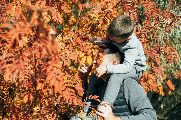 Feliz padre e hijo divirtiéndose en el parque de otoño. Familia, infancia, estilo de vida, estación, otoño concepto de otoño - Foto, Imagen