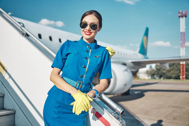 Веселая симпатичная стюардесса, работающая на самолете в солнечный день. - Фото, изображение
