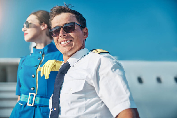 Ευτυχισμένος νεαρός πιλότος που ξεκουράζεται μετά την πτήση με συνάδελφο σε εξωτερικούς χώρους - Φωτογραφία, εικόνα