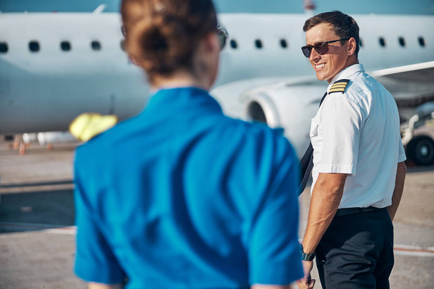 Vidám jóképű pilóta stewardess séta a jet - Fotó, kép