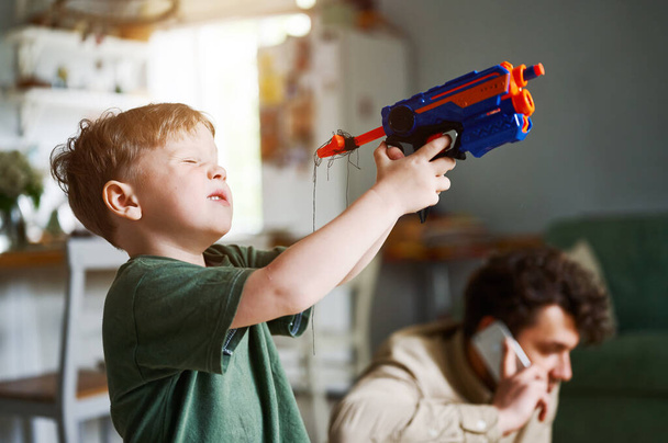 Young caucasian preschool boy playing with plasik toy, kid with colorful pistol or gun - Foto, Imagen