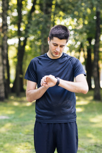 Sport man looking smart watch. Man runner using smart watch. Handsome guy tracking result after workout. Portrait of fitness man checking result - Photo, Image