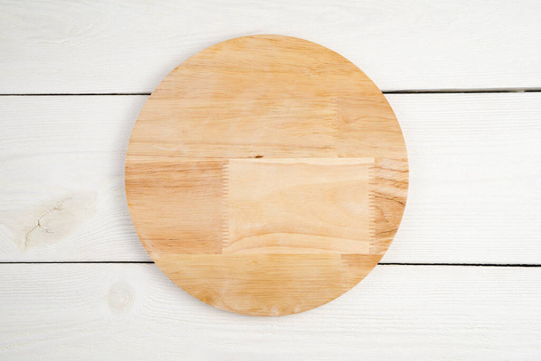 Tabla de cortar redonda de madera hecha de madera natural, sobre un fondo claro. - Foto, imagen
