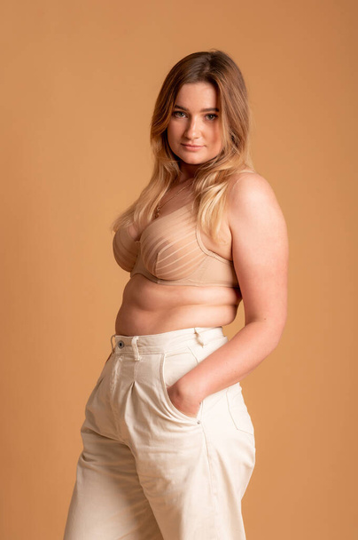 Beautiful overweight woman in beige swimsuit on pink background - Zdjęcie, obraz