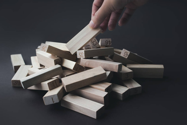 Hand pulls a wooden block from a pile of the same blocks. Leader, individuality, best worker, best employee, idea, team - Photo, Image