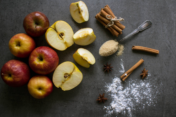 アップルパイ成分トップビューの写真。テーブルの上に赤リンゴ、卵、シナモンスティック、バター、黒糖. - 写真・画像