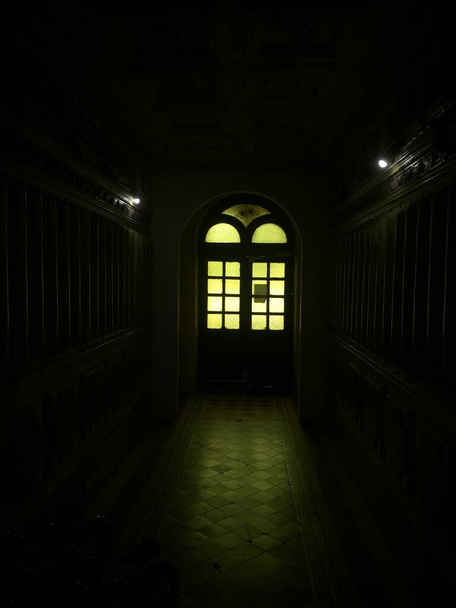 Donkere gang. Een deur met glas in lood ramen. Behang. - Foto, afbeelding