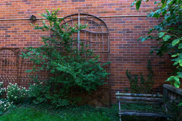 Metallitangot ikkunoihin tai oviin, jotka nojaavat tiiliseinään julkisessa puutarhassa - Valokuva, kuva
