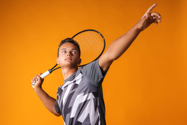 Portrait of a young man tennis player on orange background - Φωτογραφία, εικόνα