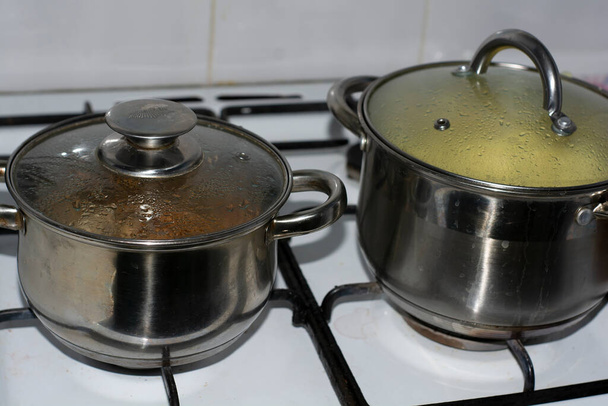 ストーブの上に2つの金属鍋でジャガイモと肉を茹でて. - 写真・画像