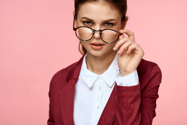 Zakelijke vrouw rood jasje bril executive lifestyle studio roze achtergrond - Foto, afbeelding