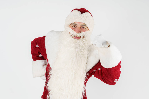 Christmas and New Years concept. Santa Claus shows a YES gesture with his hand on his knees. Isolated background. - Foto, imagen