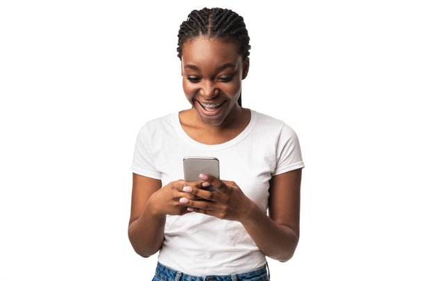 Podekscytowana czarna kobieta ze smartfonem za pomocą aplikacji na białym tle - Zdjęcie, obraz