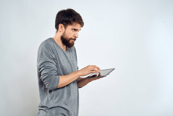 Mężczyzna z tabletem w ręku technologia internetowa komunikacja szara kurtka lekkie tło - Zdjęcie, obraz
