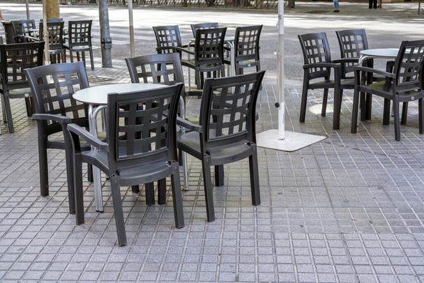 Tafels en stoelen van een bar op straat zonder dat iemand ze gebruikt. - Foto, afbeelding