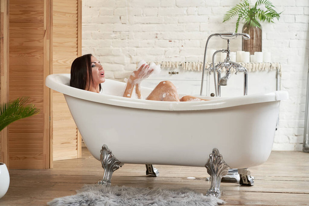Close-up portrait of a woman relaxing in the bubble bath. - 写真・画像
