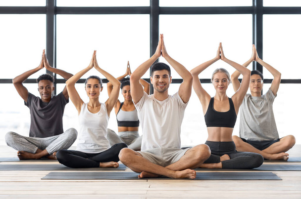 Concepto de Bienestar. Gente multicultural feliz practicando yoga en grupo en estudio moderno - Foto, imagen