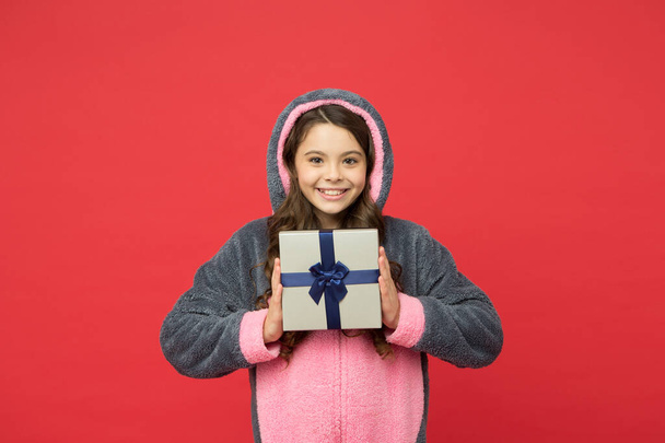 glückliches Kind trägt Kaninchen-Kigurumi und hält Überraschungsbox. Geschenke und Geschenke. Souvenir für zu Hause. sich ausgeruht und glücklich fühlen. Shop- und Shoppingkonzept. Teenie-Mädchen im Schlafanzug. Angenehmes Einkaufen - Foto, Bild
