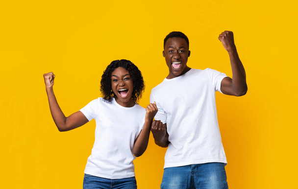 Les partenaires afro-américains se réjouissent du succès, serrent les poings et s'écrient sur le jaune - Photo, image