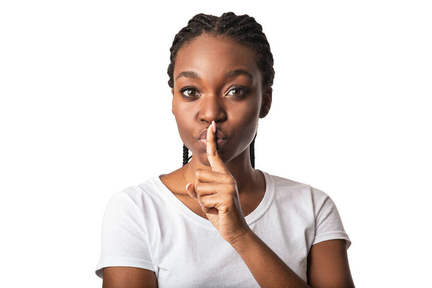 Afrykańska kobieta pokazuje Hush znak patrząc na aparat, białe tło - Zdjęcie, obraz