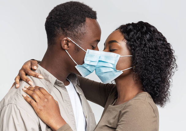 Closeup of african lovers kissing throught medical masks - Foto, afbeelding
