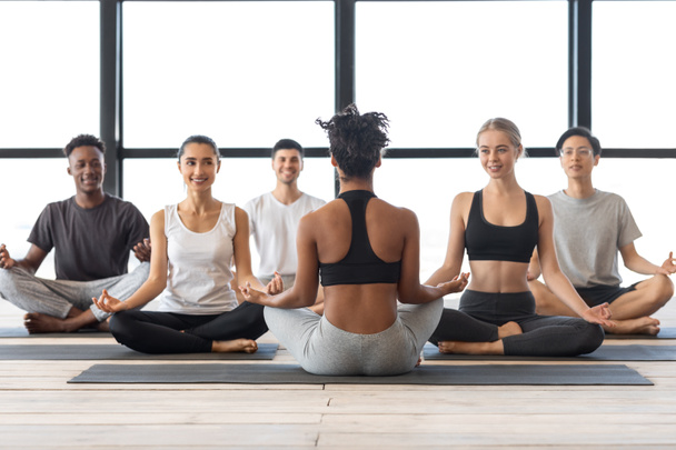Clase de yoga. Hombres y mujeres multiétnicos que tienen clase grupal con instructora femenina - Foto, imagen