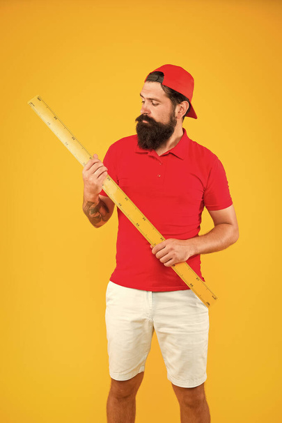 Measuring with ruler. Size measurement. Measuring length. Sizing clothes. Student study stem disciplines. Long ruler tool equipment. What about your size. Bearded man with big measuring instrument - Φωτογραφία, εικόνα